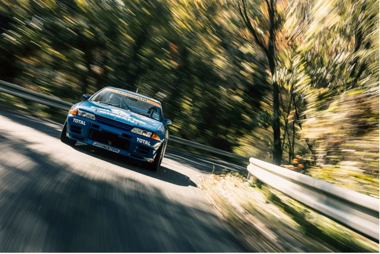 青い日産スカイラインGT-R R32が山道を走行する様子