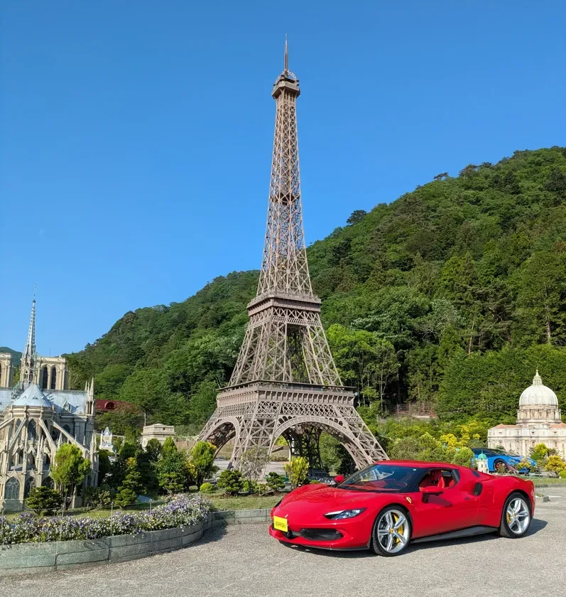 ミニチュアパークで、エッフェル塔とノートルダム大聖堂の模型、そして赤いフェラーリが並ぶ光景